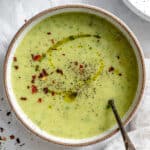 a bowl of vegan zucchini soup in a white bowl.