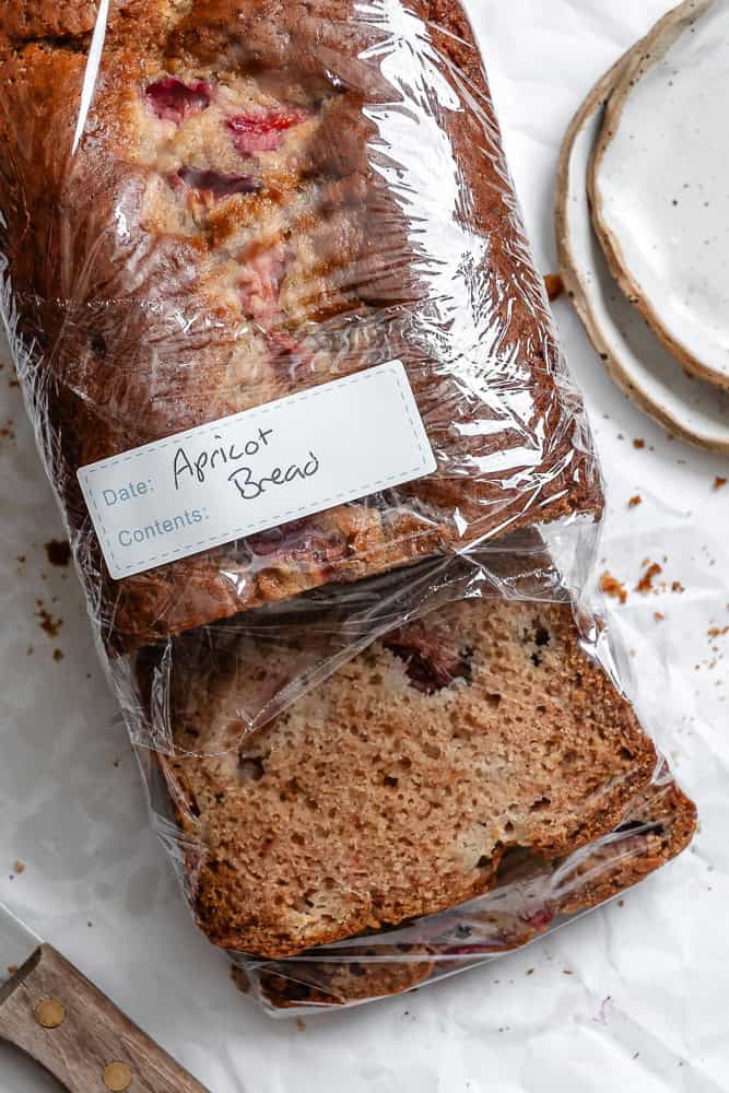 completed Easy Apricot Bread on a white surface in plastic wrap