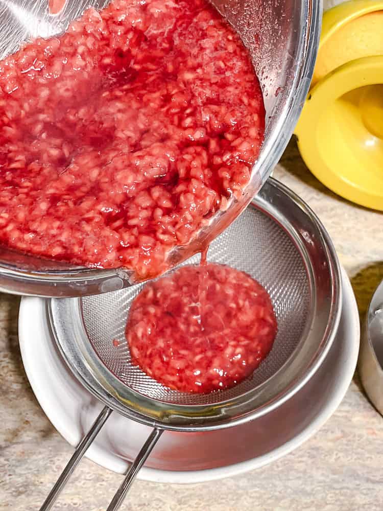 staining raspberry sauce through a fine mesh sieve.