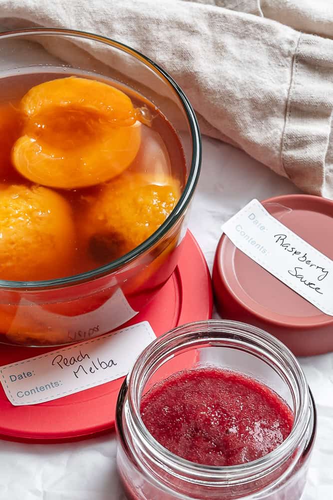leftover poached peaches and raspberry sauce in individual storage containers.
