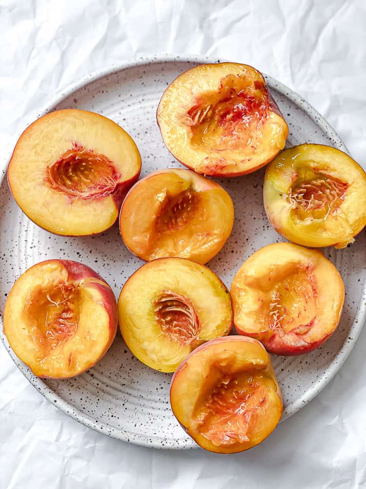 halved and pitted peaches on a plate.
