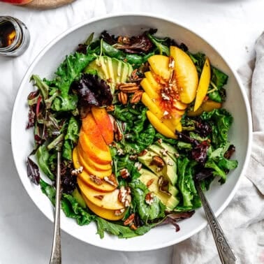 close up on a peach salad in a large white bowl.