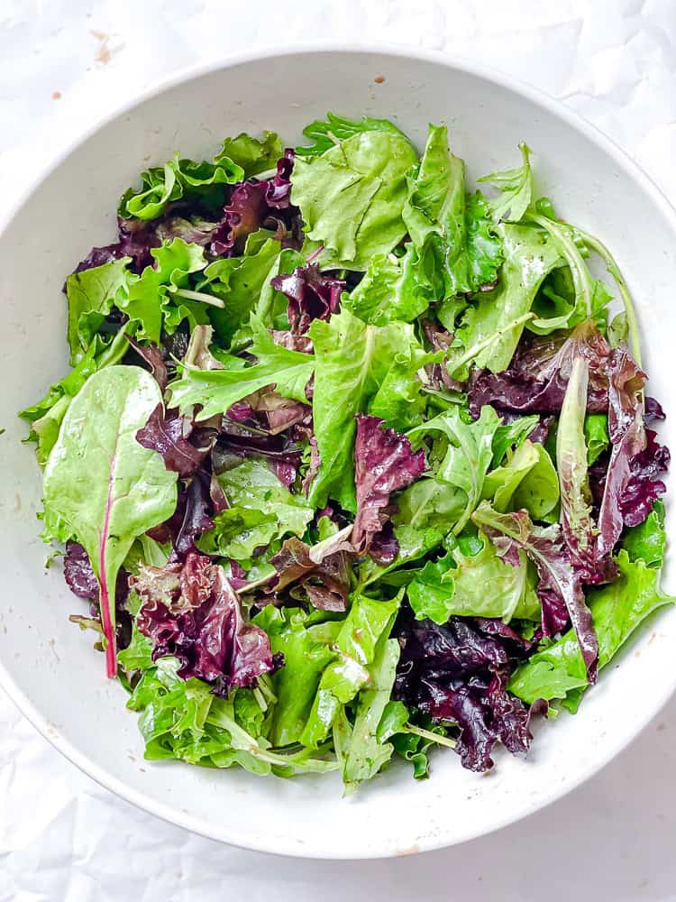 salad greens in a large white bowl.