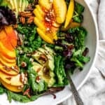 close up on a peach salad in a large white bowl.