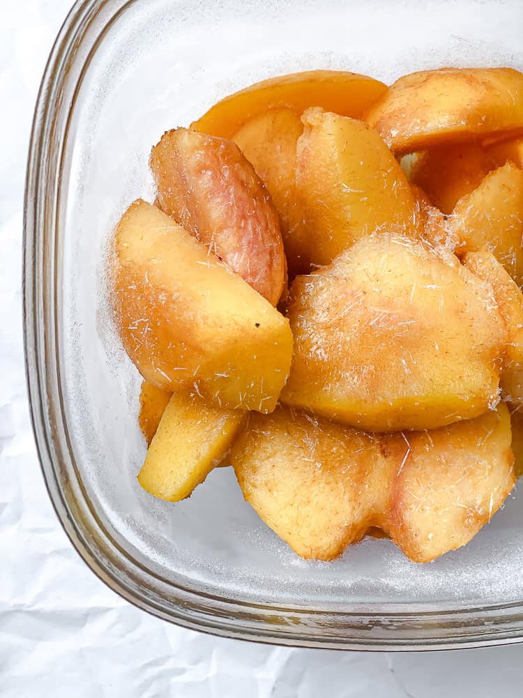 frozen peach slices in a glass container.