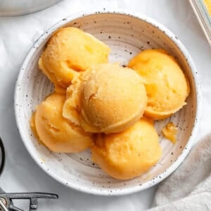 5 scoops of peach sorbet in a white bowl.