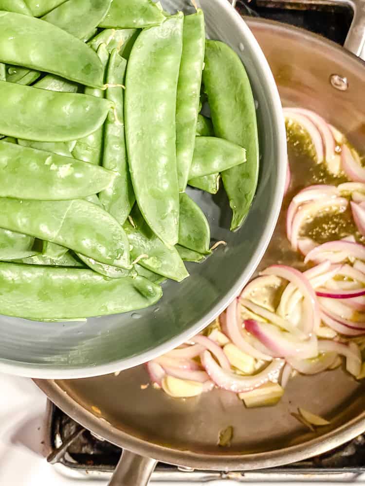 process shot of adding snap peas to pan