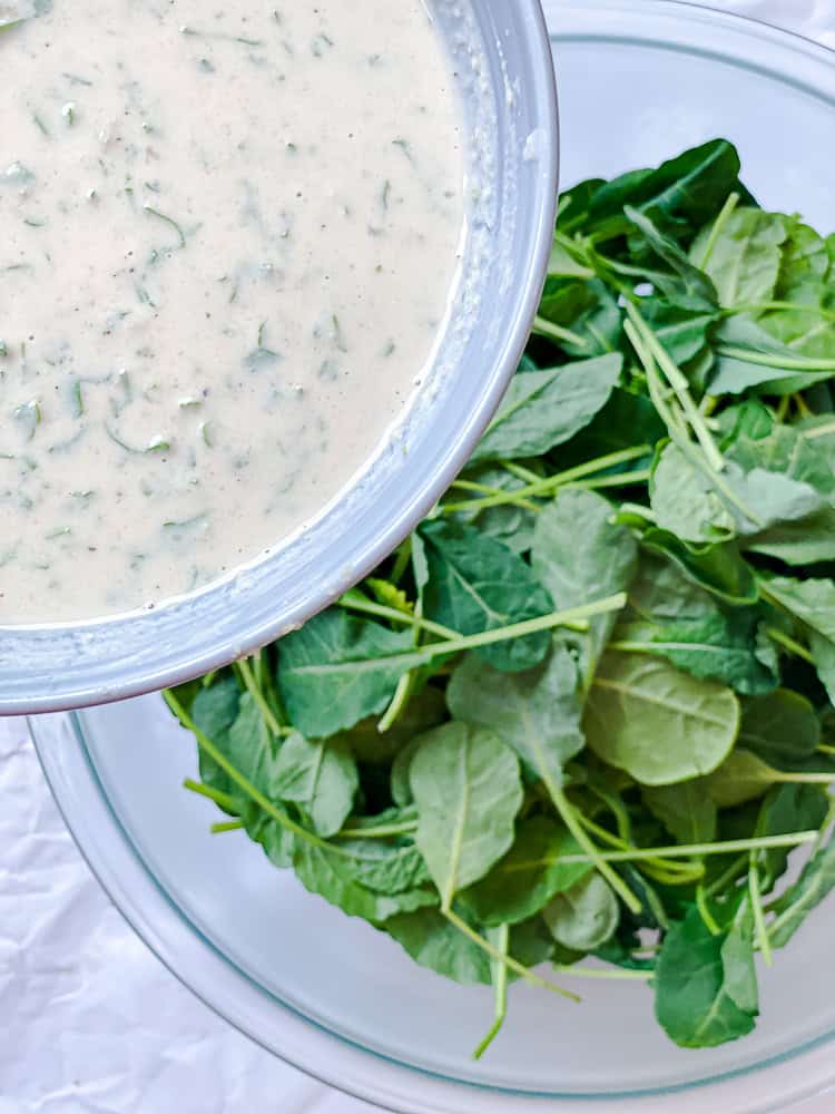 process shot showing adding dressing to kale