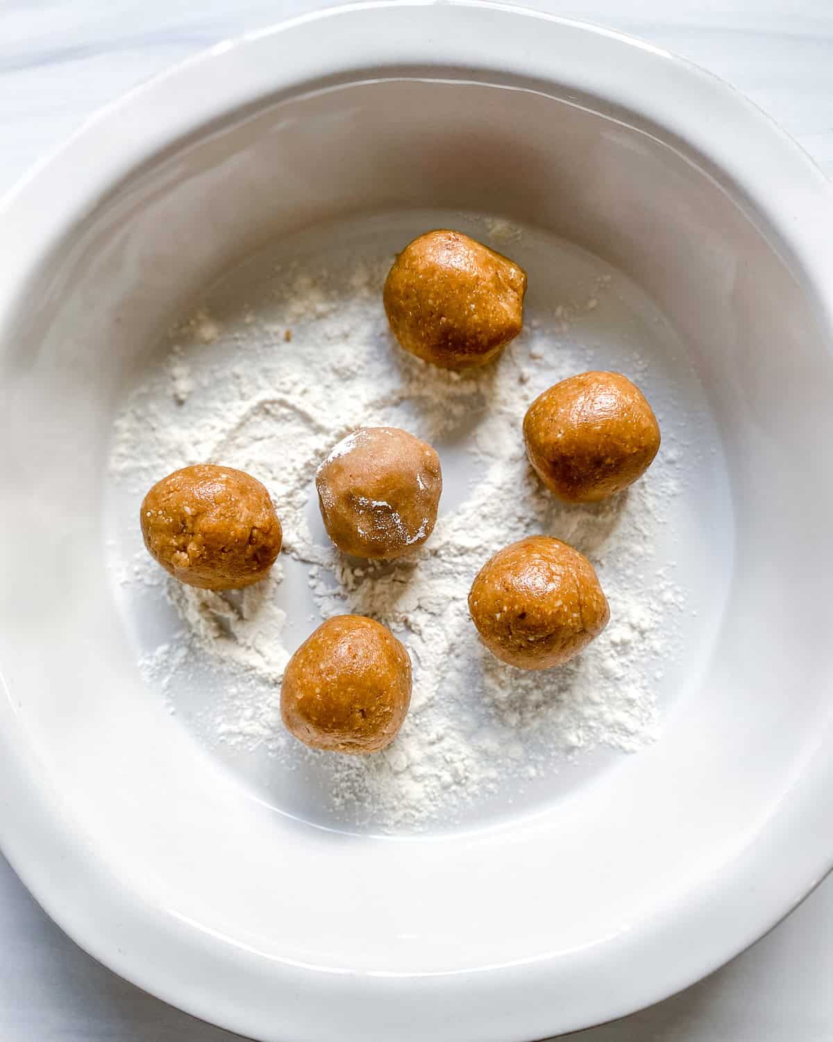 process shot showing rolling peanut butter balls in flour