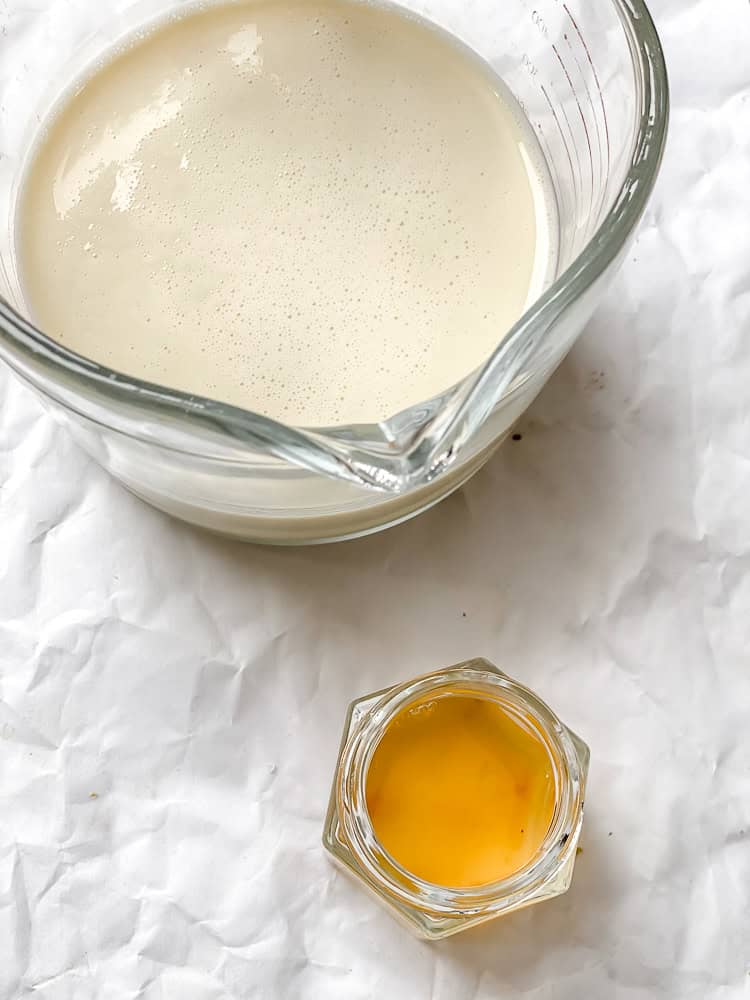 plant milk and apple cider vinegar in separate containers on white surface