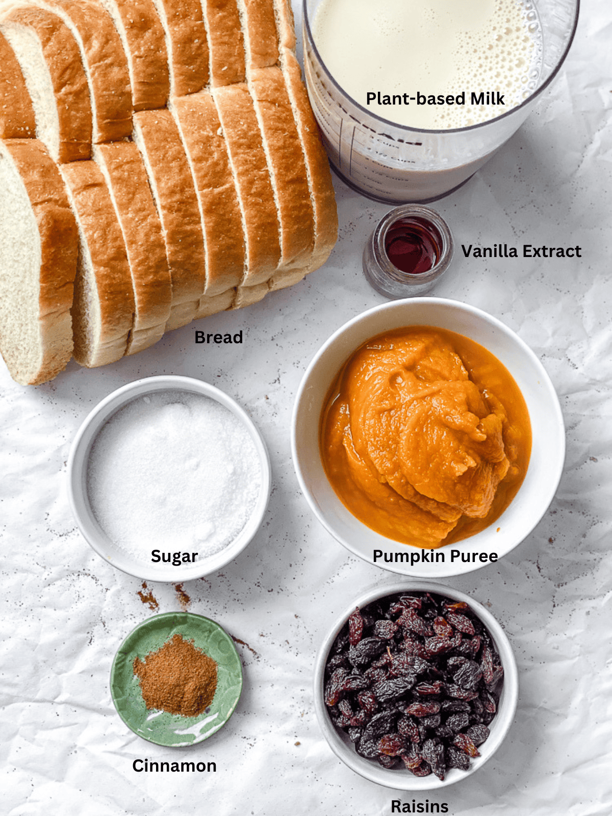 ingredients for Pumpkin Bread Pudding measured out on a white surface