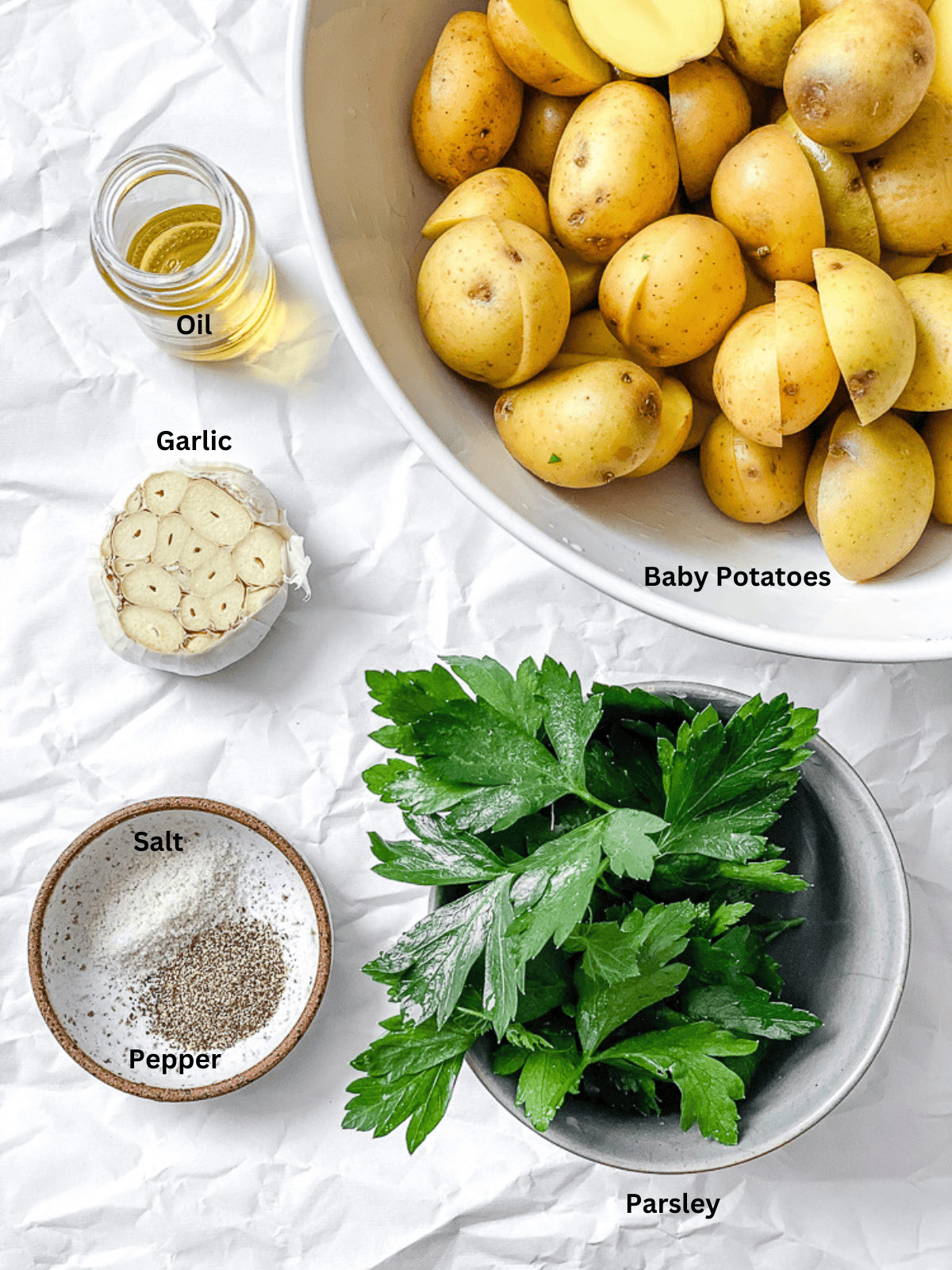 ingredients for Garlic Roasted Baby Potatoes measured out on a white surface