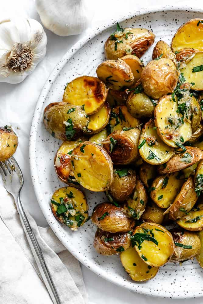 Garlic roasted baby potatoes with parsley served on a plate.