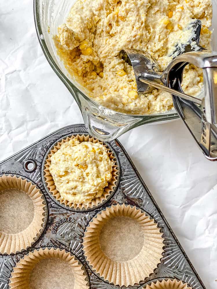 process shot showing scooping batter into muffin tin