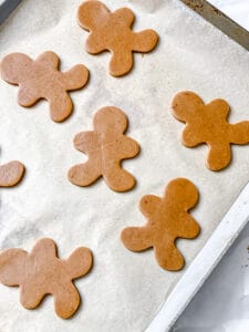 Unbaked vegan gingerbread men on a lined baking sheet