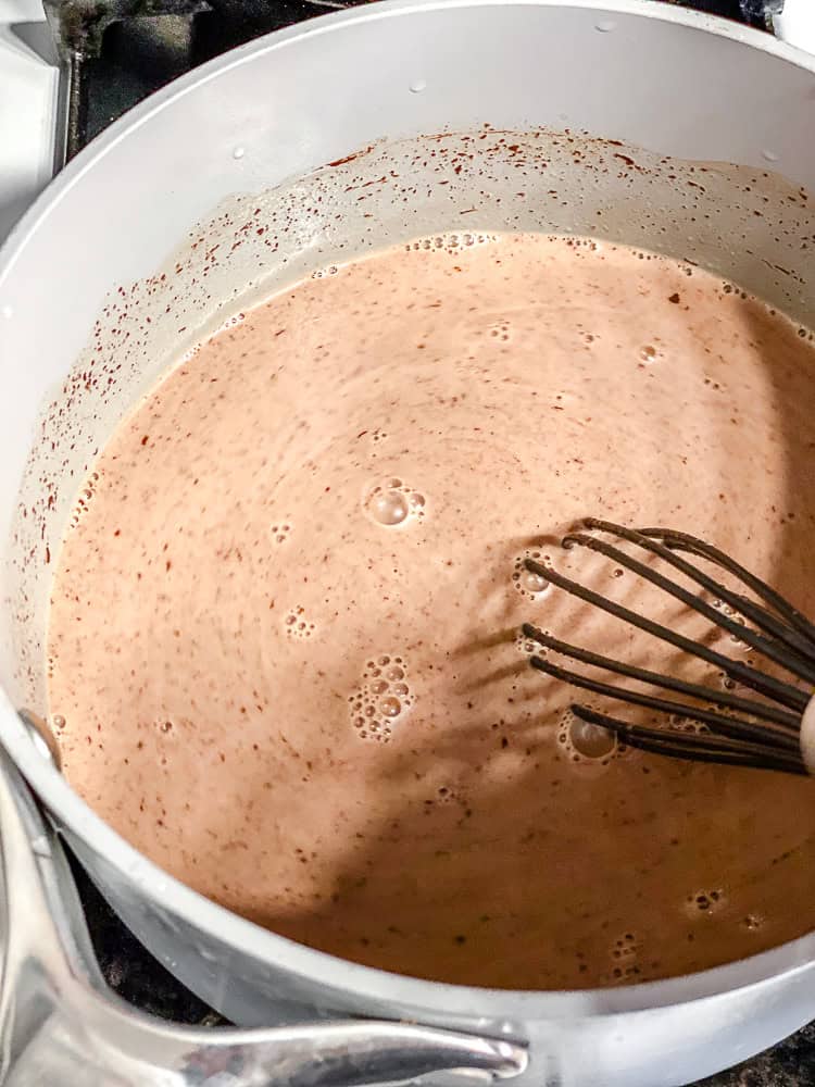 Whisking melted chocolate into plant-based milk in a saucepan