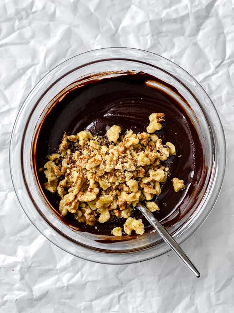 process shot showing mixing walnuts into bowl of chocolate