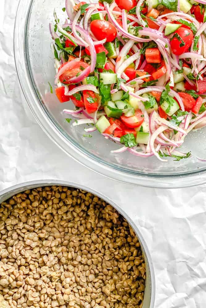 process shot showing two bowls with lentils and the other with salad ingredients on a white surface
