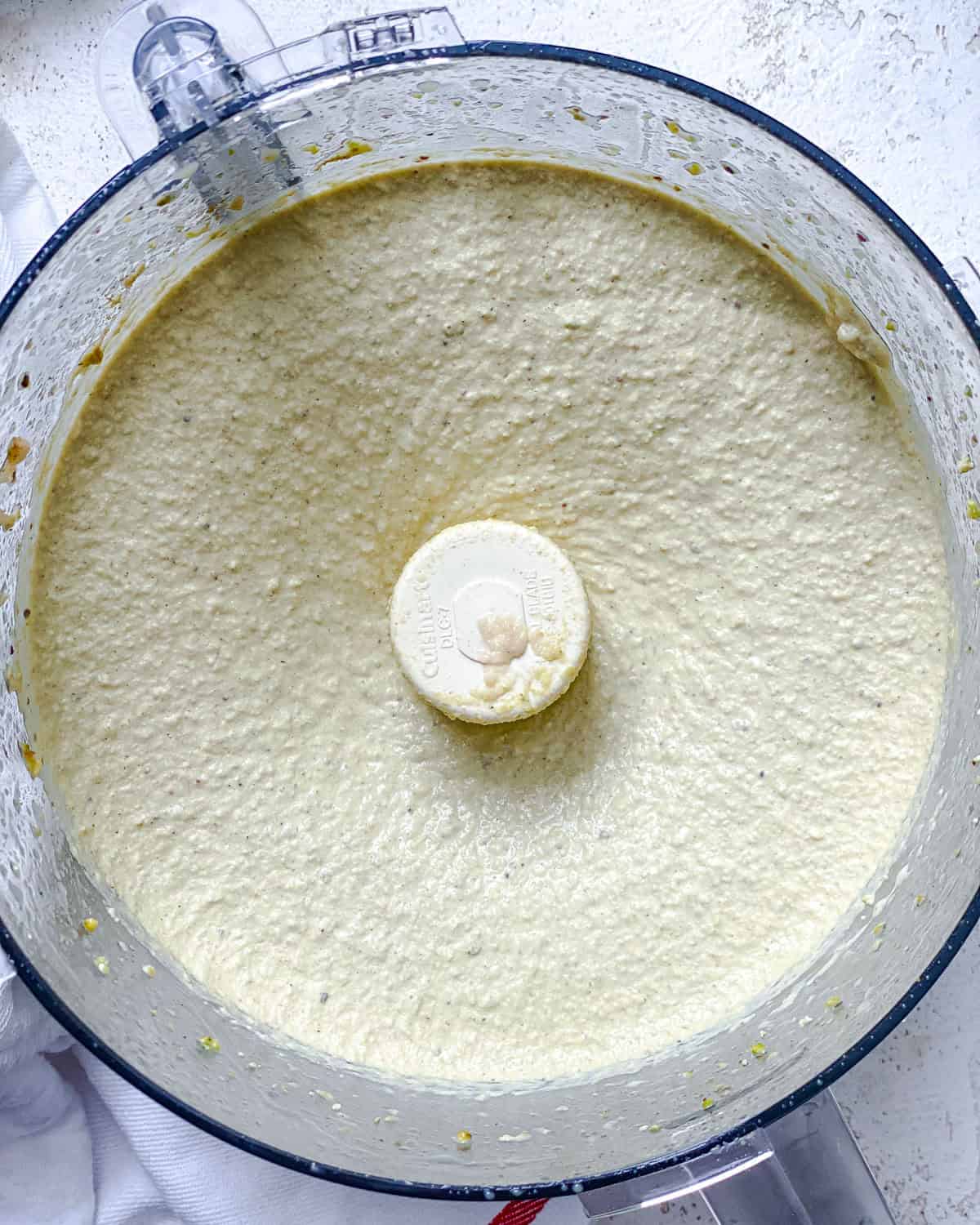 Process shot showing post processed pistachio hummus in container.