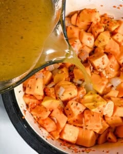 Process shot of adding veggie broth to pot.