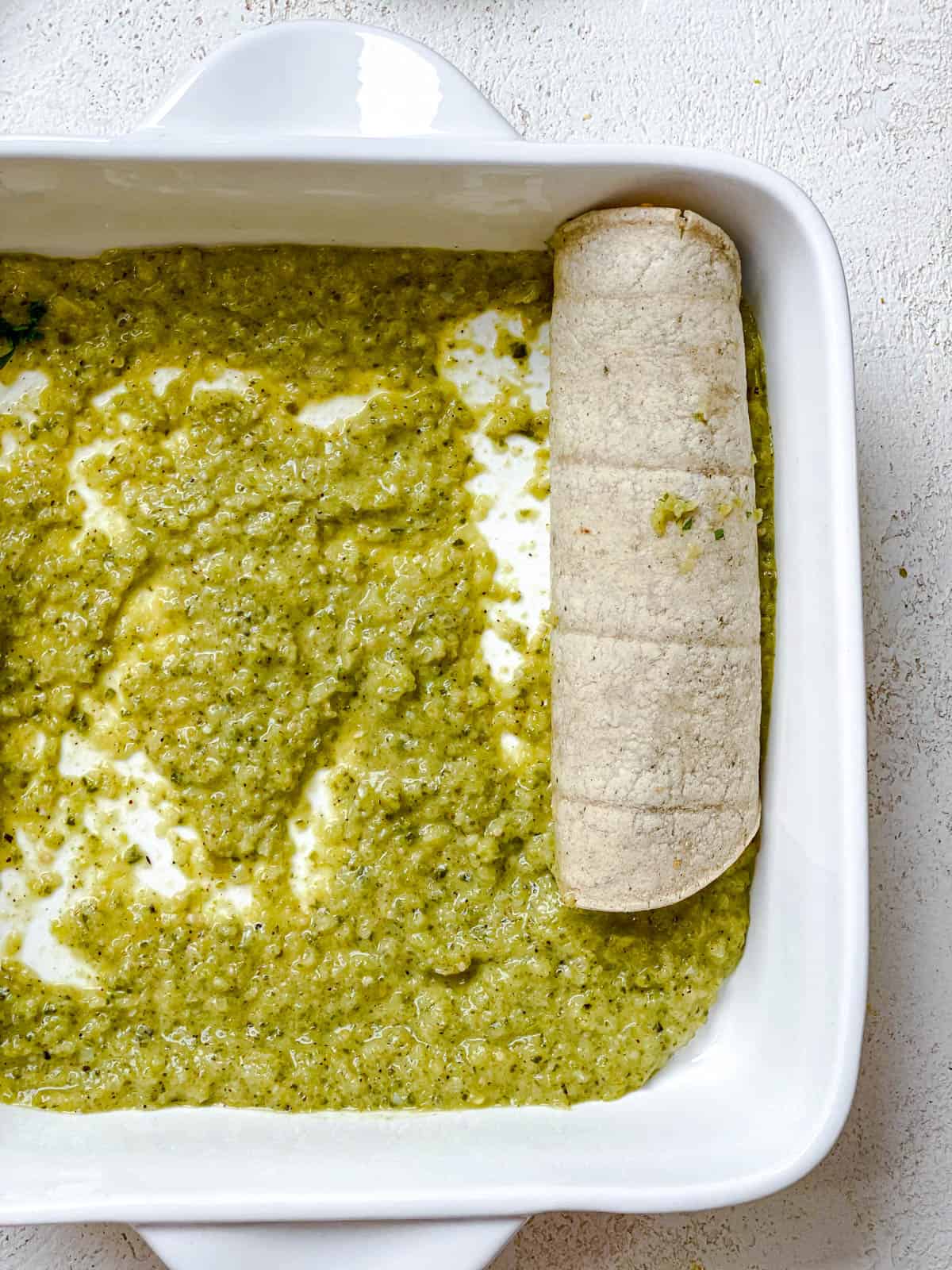 process shot showing enchilada being assembled into baking dish