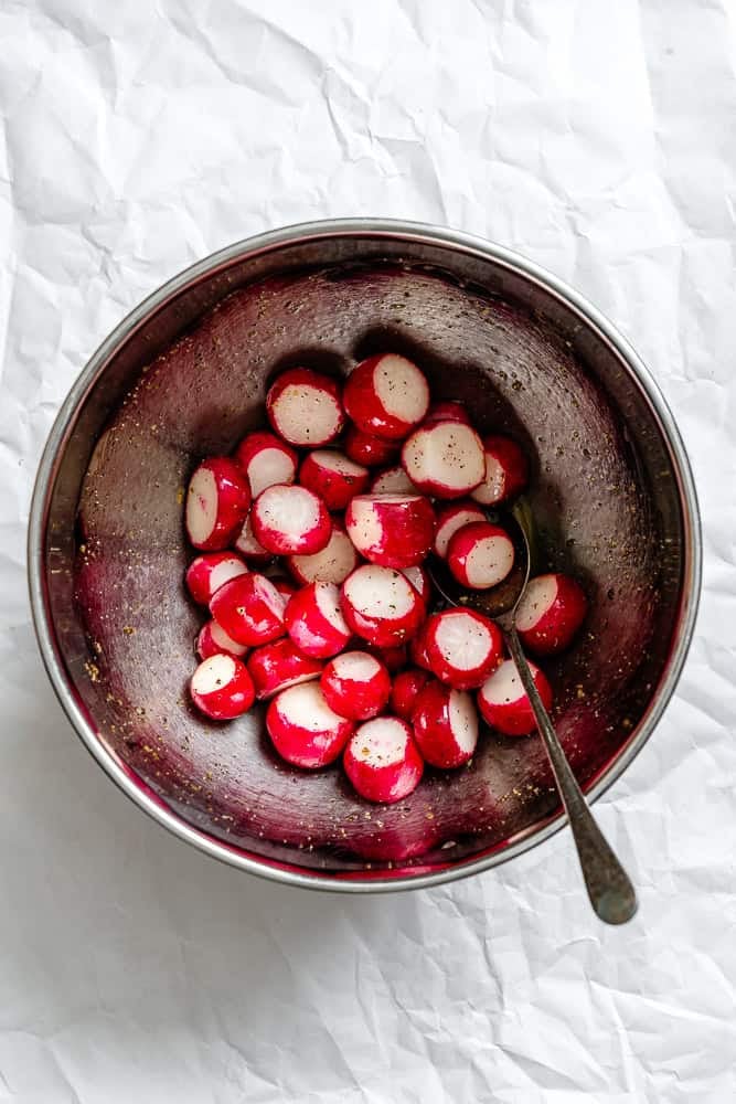 Process shot showing radishes in a bowl.