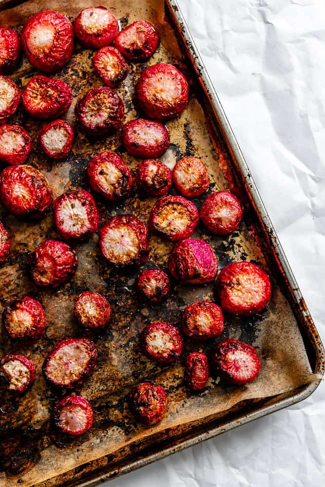 Process shot showing post roasted radishes on baking sheet.