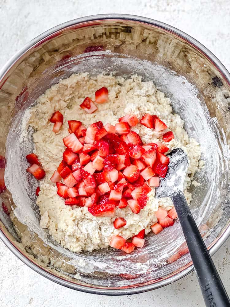 Process shot showing strawberries added to bowl.