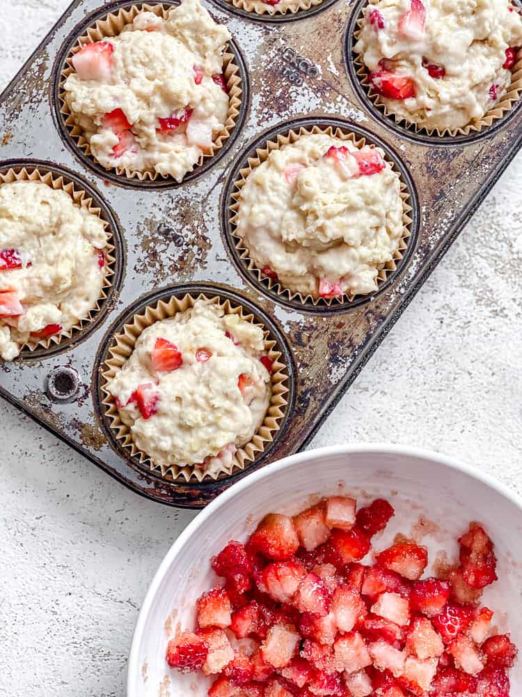 Process shot showing adding strawberry topping to muffins.