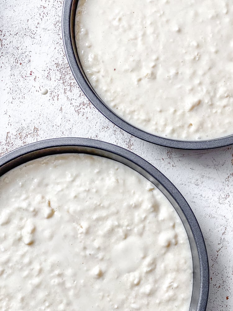 Process shot showing batter added to two cake pans.