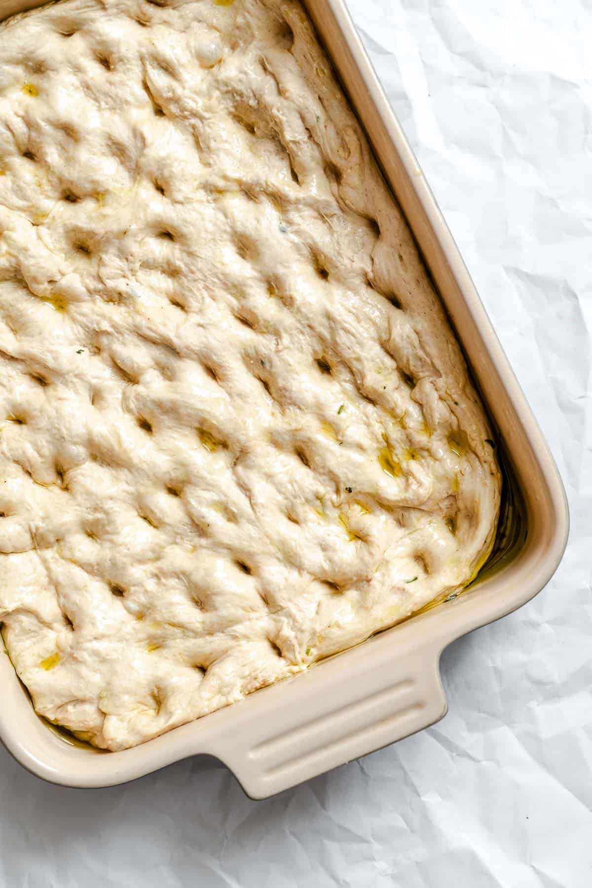 Process shot showing dimples made in dough in baking dish.