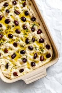 Process shot showing pre-baked Vegan Focaccia (Garlic and Herb) in baking dish.