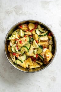 Process shot showing veggies added to bowl.