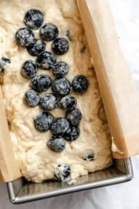 Process shot showing batter and blueberries added to bread pan.