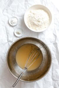 Process shot showing ingredients being added to stainless steel bowl.