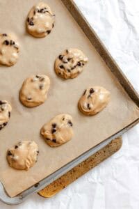 Process shot showing unbaked cookies added to baking tray.