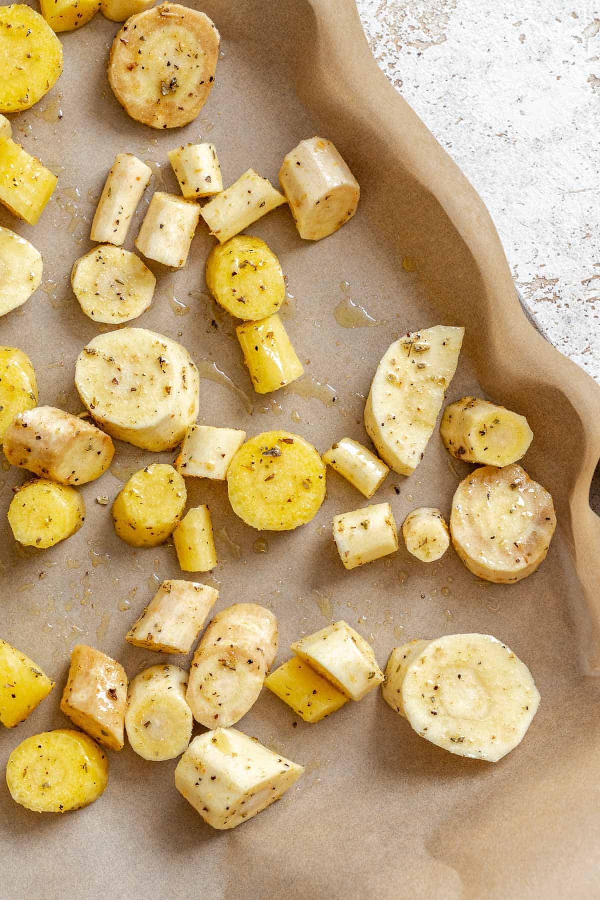 Process shot showing parsnips added to baking tray.