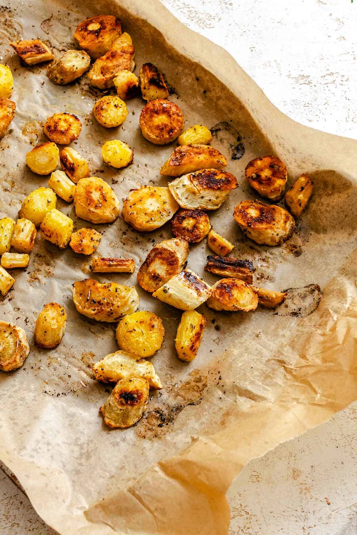 Process shot showing post baked roasted parsnips on baking tray.