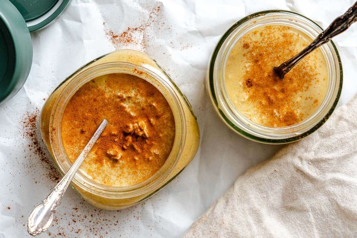 Two completed containers of Pumpkin Pie Overnight Oats with spoon inside.