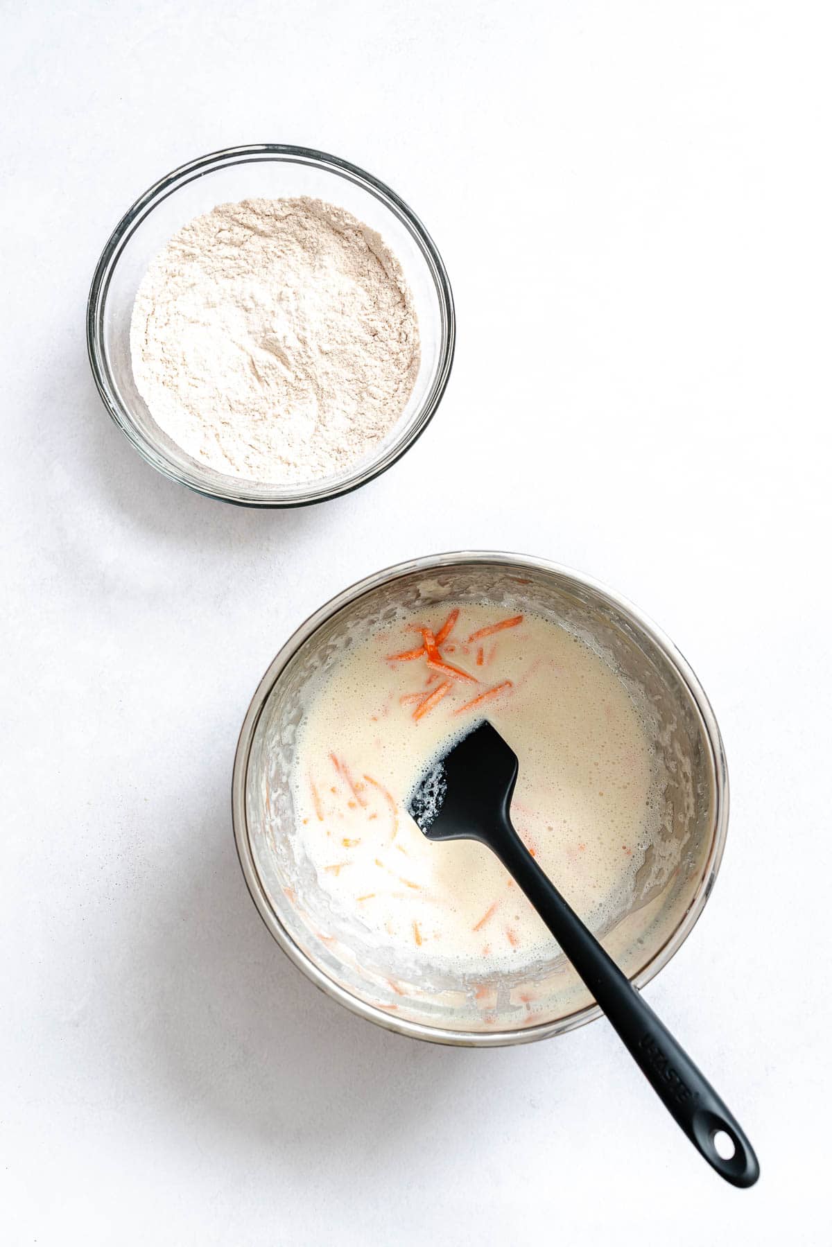 Process shot showing mixing ingredients for Carrot Cake Pancakes in a bowl.