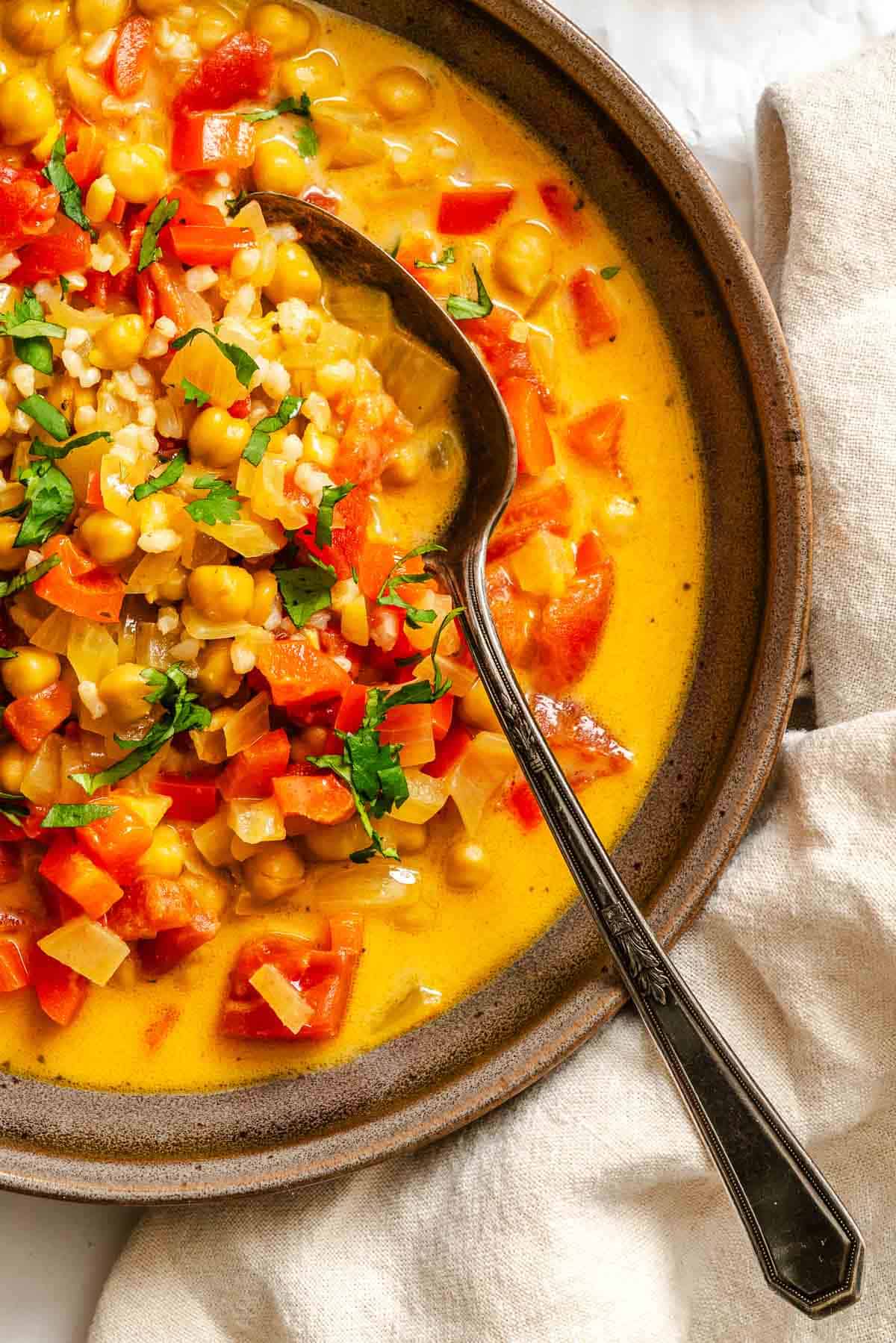 Completed Coconut Chickpea Curry Soup in pot on white surface.