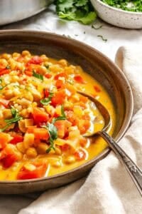 Completed Coconut Chickpea Curry Soup in bowl on white surface.