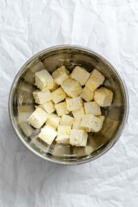 Process shot showing tofu with seasoning mixed together in a bowl.