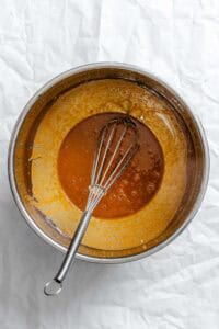 Process shot showing peanut sauce being whisked in a bowl.