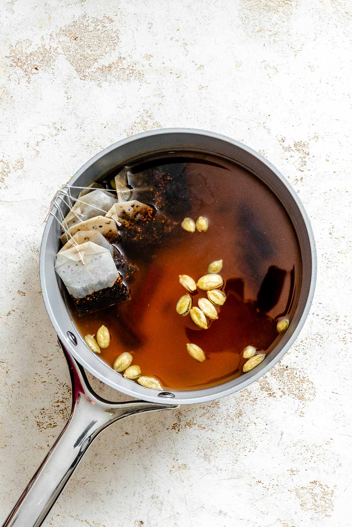 Process shot showing ingredients for Homemade Chai Concentrate in a pan.