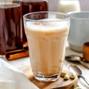 Completed Homemade Chai Concentrate in a glass and several jars.