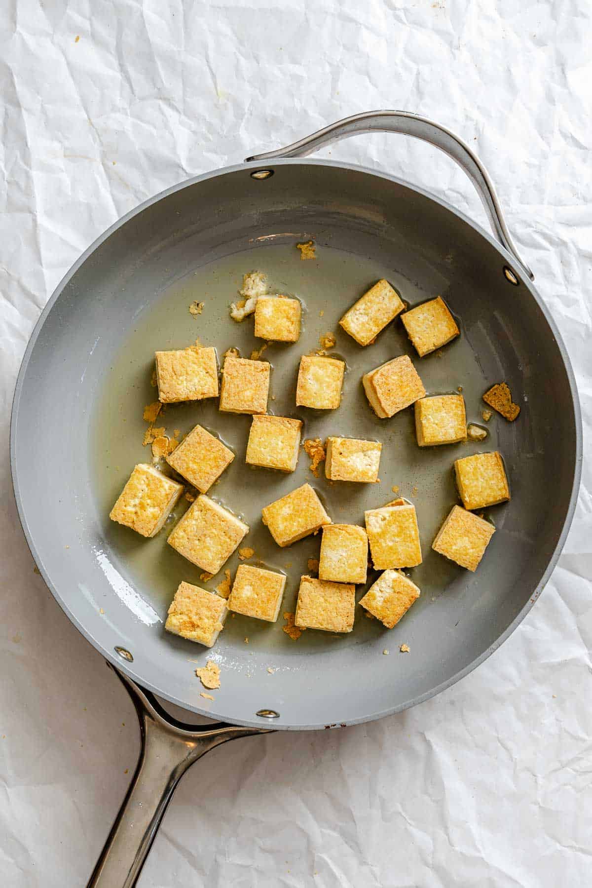 Process shot showing tofu cooking on pan.