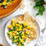 Completed Mango Cucumber Salsa on a plate against a white surface.