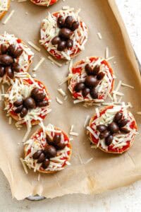 Process shot showing pre baked Mini Spider Pizza [Bagel Bites] on baking tray.