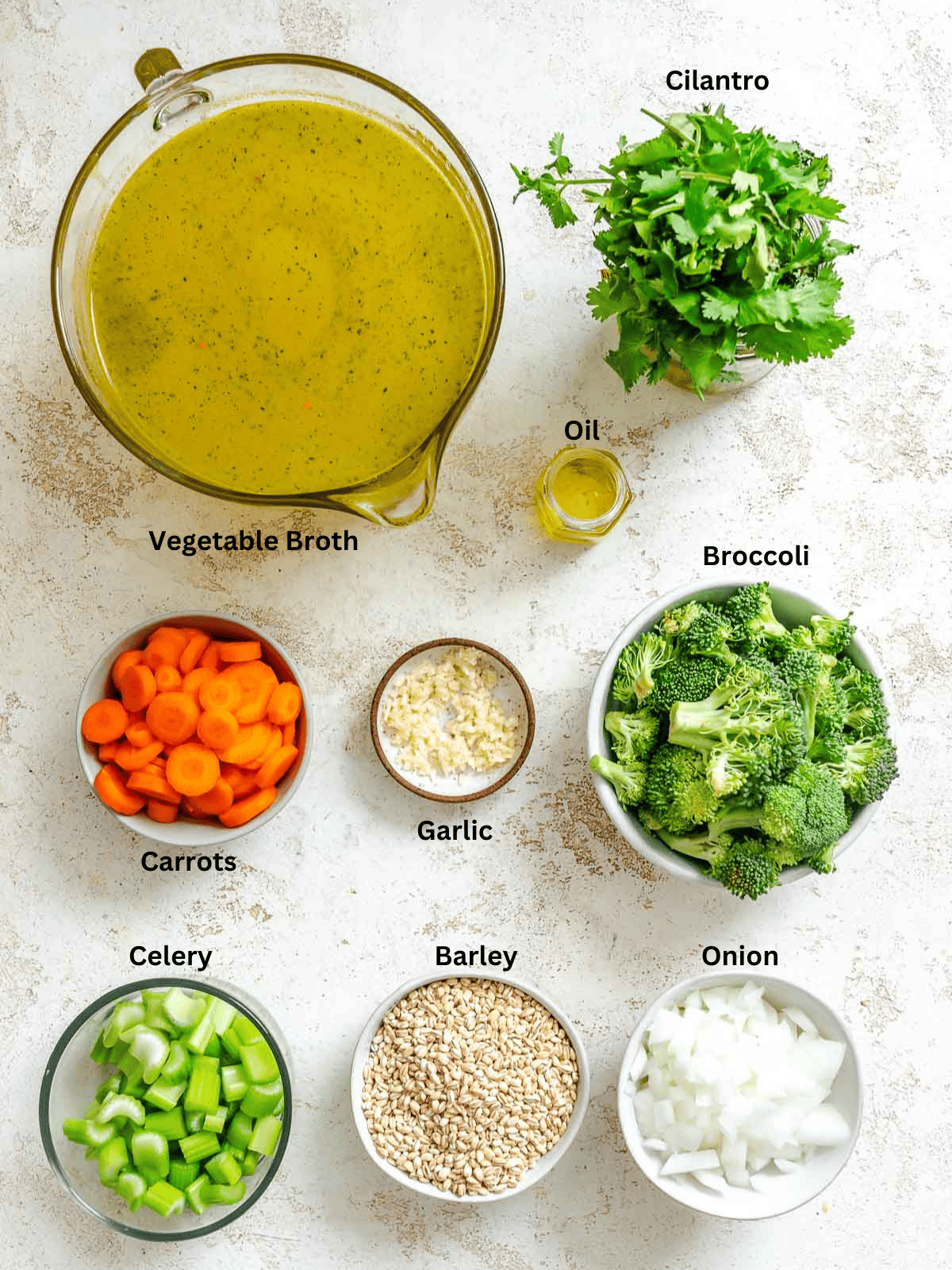 Ingredients for Vegetable Barley Soup measured out on a white surface.
